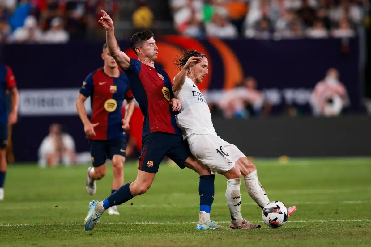 Real Madrid midfielder Luka Modric and Barcelona forward Robert Lewandowski battle for possession.